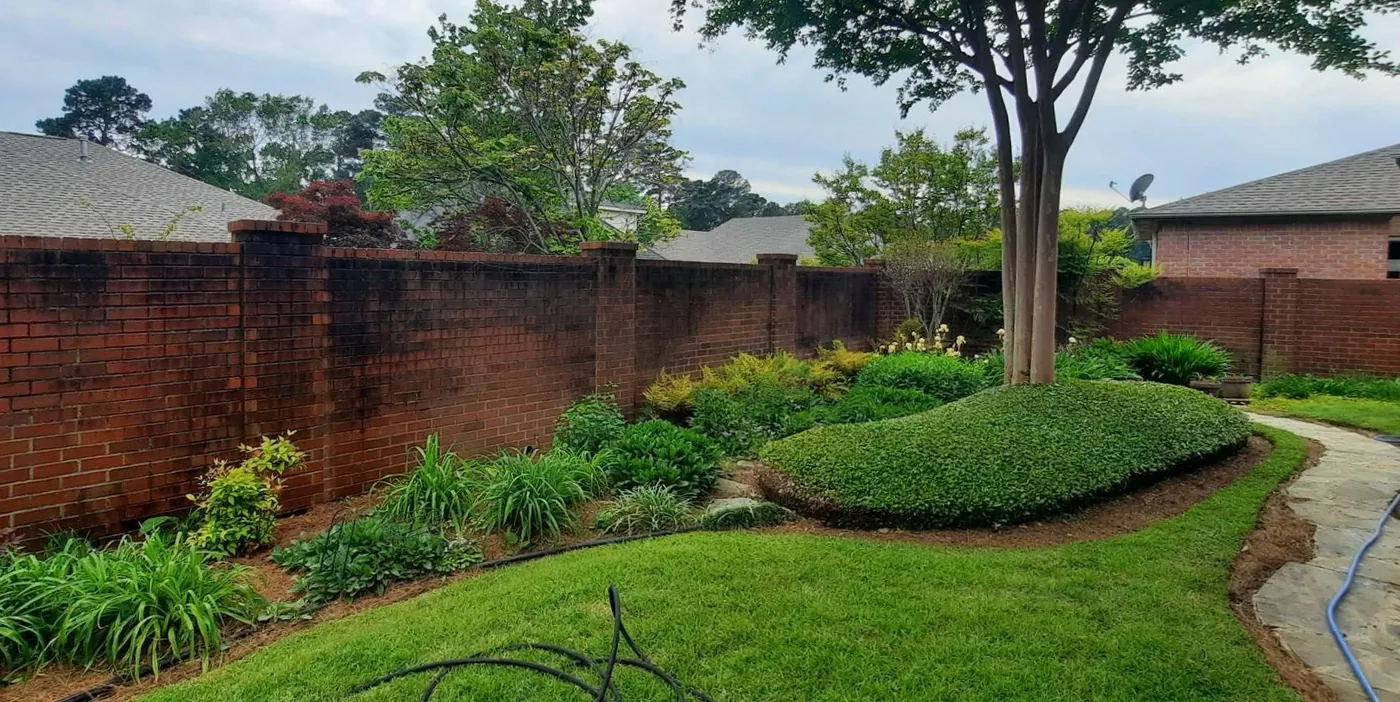 Before: long brick privacy wall cleaned of dark mildew by B&H