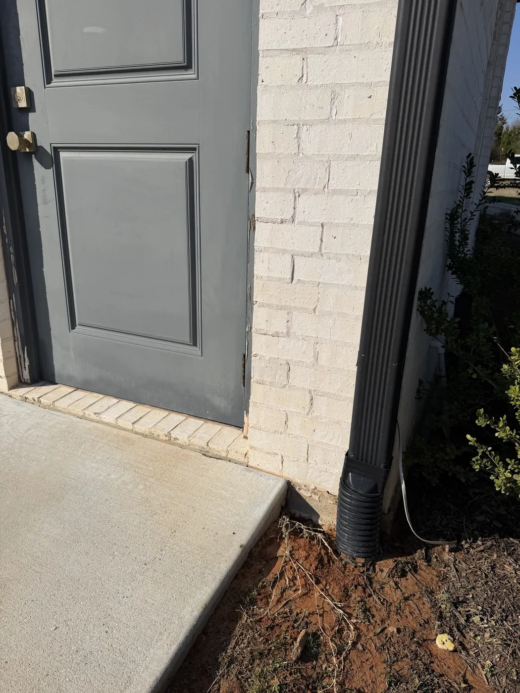 After: white brick home with orange rust stains along the foundation, cleaned by B&H