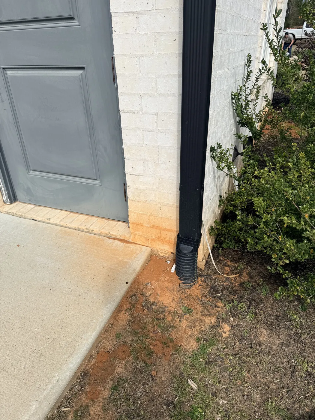 Before: white brick home with orange rust stains along the foundation, cleaned by B&H