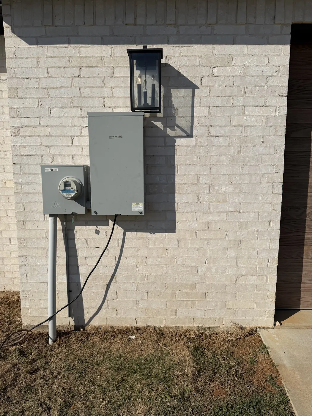 After: rust-stained white brick wall below an electric meter, restored by B&H