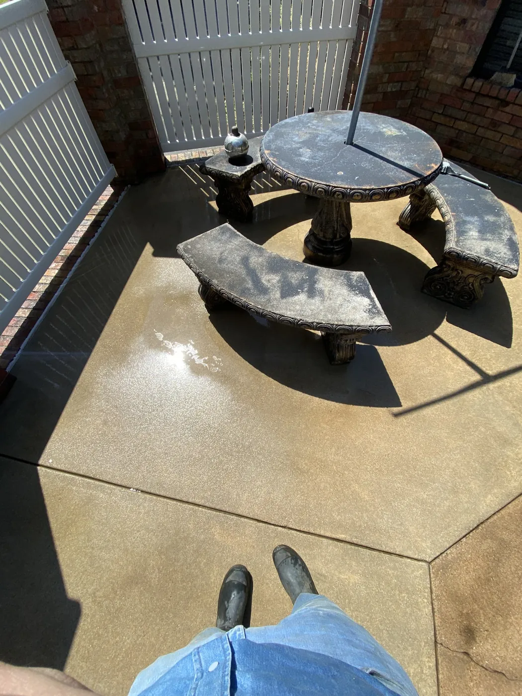 After: backyard concrete patio with round table, cleaned by B&H