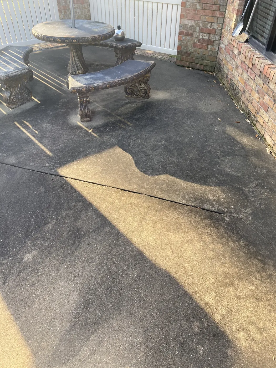Before: backyard concrete patio with round table, cleaned by B&H